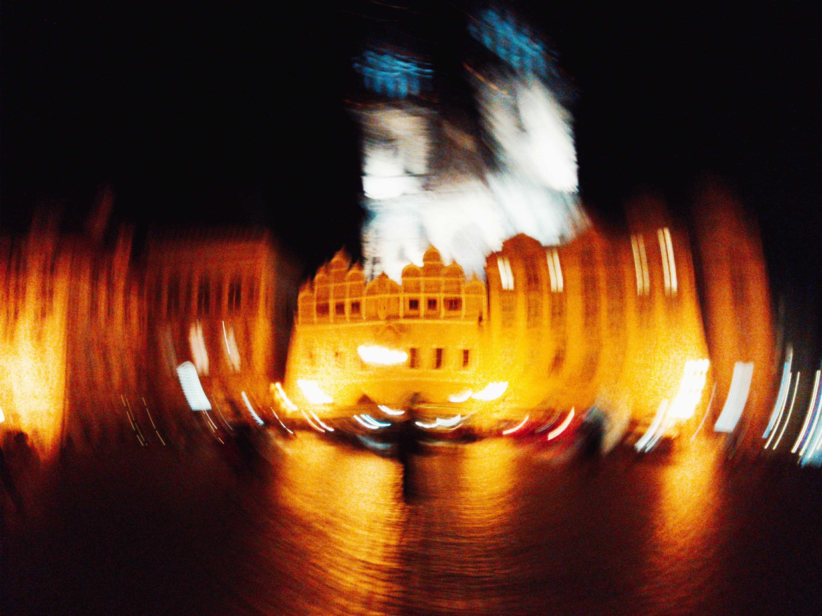Illuminated building at night, golden motion blur reflected on water