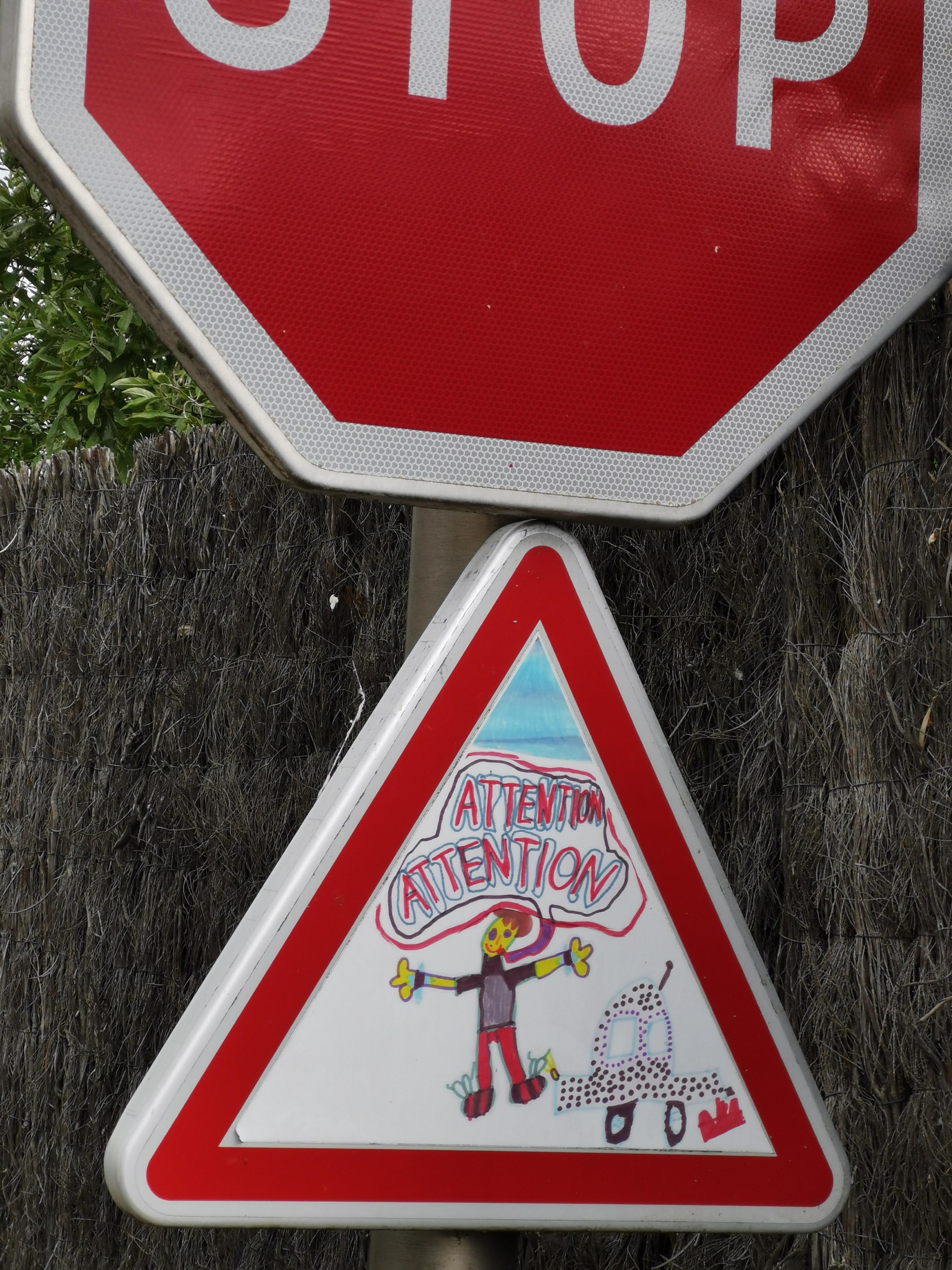 STOP sign with a hand-drawn 'ATTENTION' warning sign below it